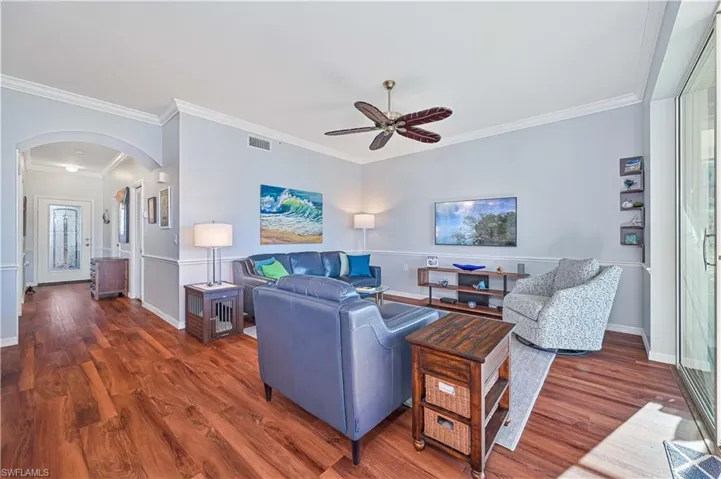 Living room with dark hardwood / wood-style floors, ceiling fan, and crown molding