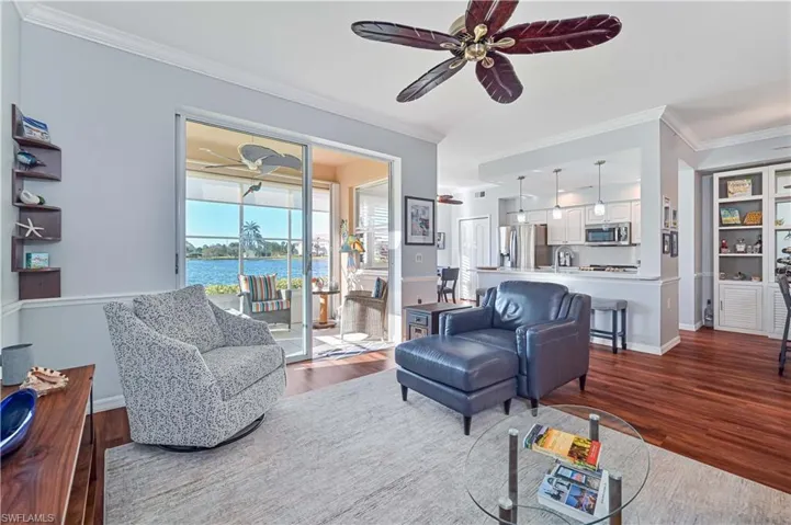 Living room with a water view, hardwood / wood-style flooring, crown molding, and sink