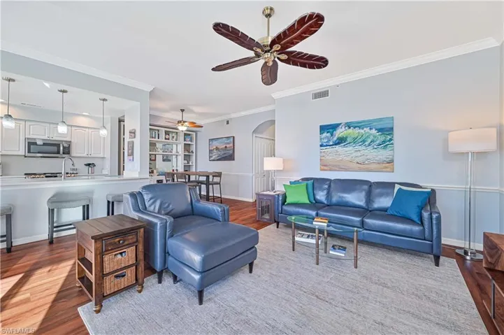 Living room featuring ceiling fan, wood-type flooring, and crown molding