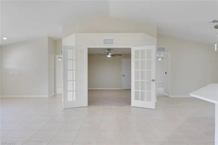 Unfurnished room featuring french doors, vaulted ceiling, a ceiling fan, and light tile patterned flooring