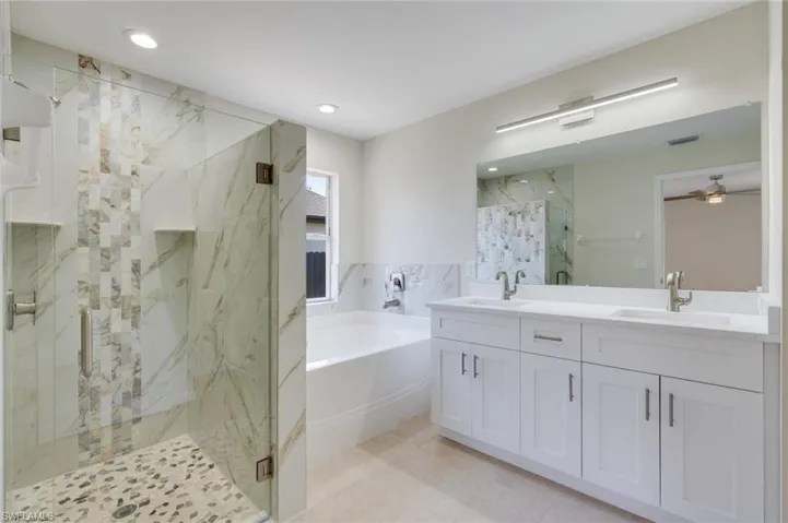 Full bathroom featuring double vanity, a marble finish shower, a garden tub, recessed lighting, and a ceiling fan
