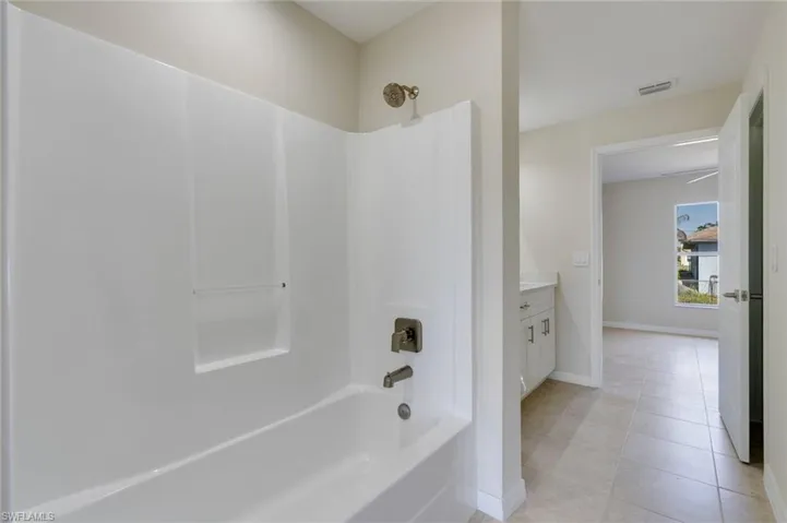 Full bath featuring vanity, shower / tub combination, and light tile patterned flooring