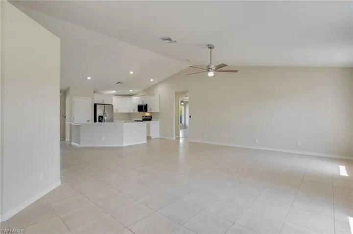 Unfurnished living room featuring ceiling fan, light tile patterned floors, and a high ceiling