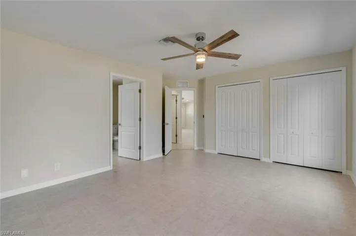 Unfurnished bedroom featuring two closets, a ceiling fan, and connected bathroom