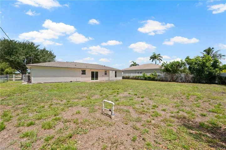 Expansive backyard with a large grassy area, privacy fencing, and mature trees