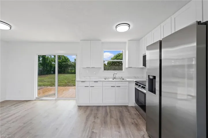 Modern kitchen featuring white shaker cabinetry, stainless steel appliances, and light-toned countertops with a matching backsplash