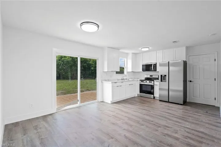 Contemporary kitchen with white cabinetry, stainless steel appliances, and light-toned countertops