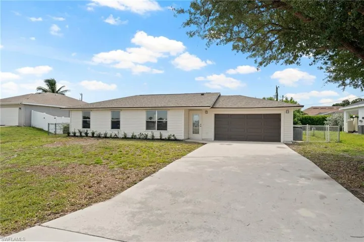 Light-colored siding home featuring a dark brown garage door, concrete driveway, and a fenced side yard