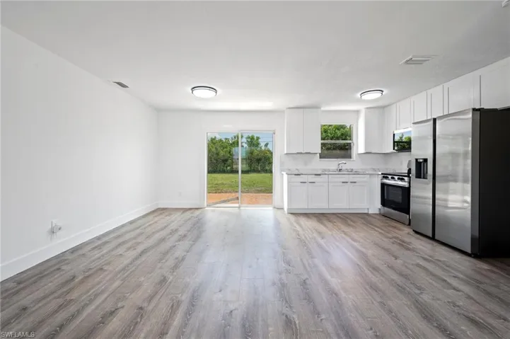 Open-concept living space featuring wood-finish flooring and a kitchen with white cabinetry