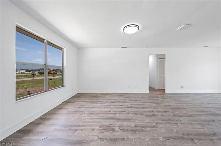 Spacious interior featuring wood-finish flooring, white walls, and a large window