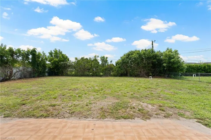 Expansive outdoor space featuring a large grassy area, perimeter fencing, and mature trees providing natural screening