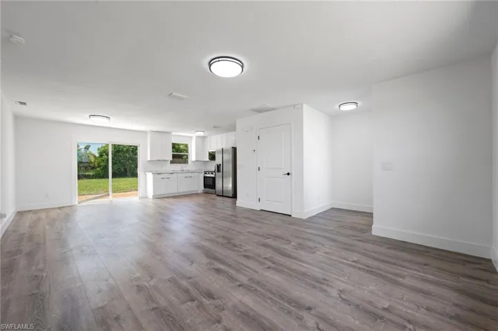 Open-concept living area featuring wood-finish flooring, white walls, and contemporary flush-mount lighting