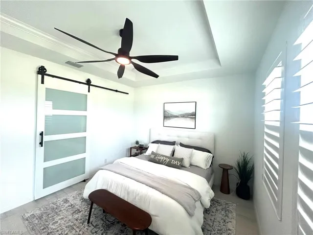 Primary bedroom with custom barn door, upgrades: tray ceiling, ceiling fan from Dan's Fans & plantation shutters & carpet