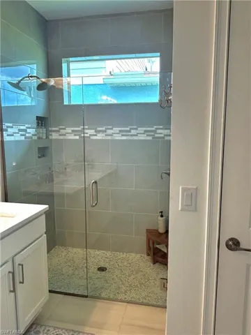 Primary walk in shower with upgrades to frameless glass shower enclosure, faucet, floor tile, floor to ceiling tile & tiled soap dish