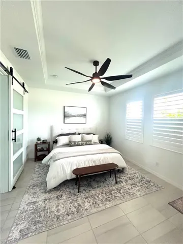 Primary bedroom with custom barn door, upgrades: tray ceiling, Dan's Fans ceiling fan, plantation shutters & carpet