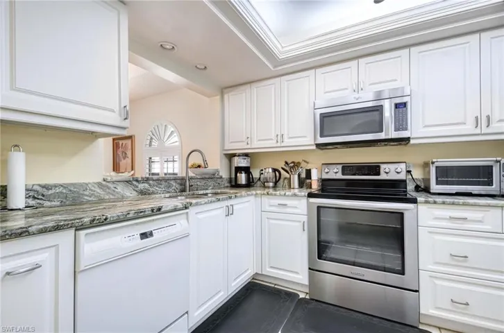 Kitchen featuring stainless steel appliances, white cabinetry, light stone countertops, recessed lighting, and crown molding