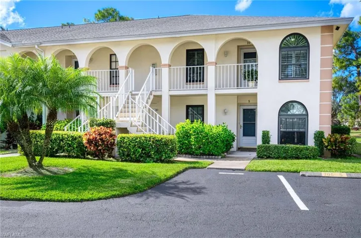 View of property featuring uncovered parking and stairs