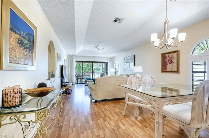Dining space featuring light wood-type flooring, ceiling fan, a textured ceiling, a chandelier, and a tray ceiling