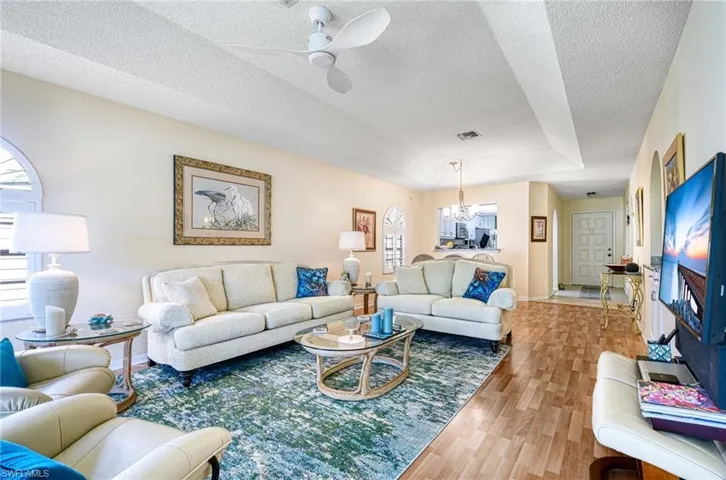 Living room featuring wood finished floors, a textured ceiling, a ceiling fan, and a chandelier