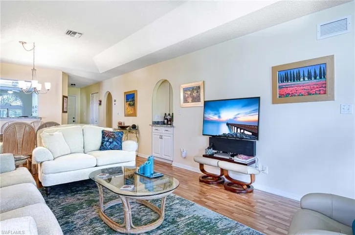 Living area featuring wood finished floors, a chandelier, arched walkways, and a textured ceiling