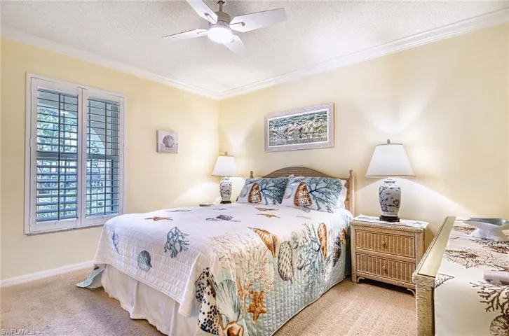 Bedroom with a textured ceiling, carpet, ornamental molding, and a ceiling fan