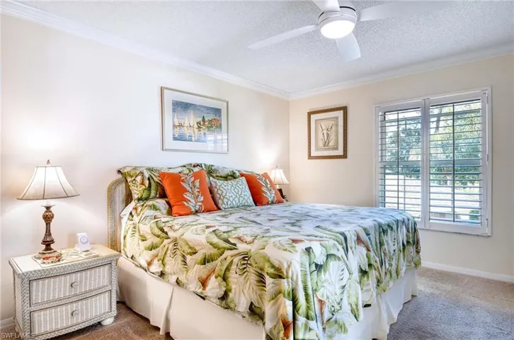 Carpeted bedroom featuring ornamental molding, a textured ceiling, and a ceiling fan