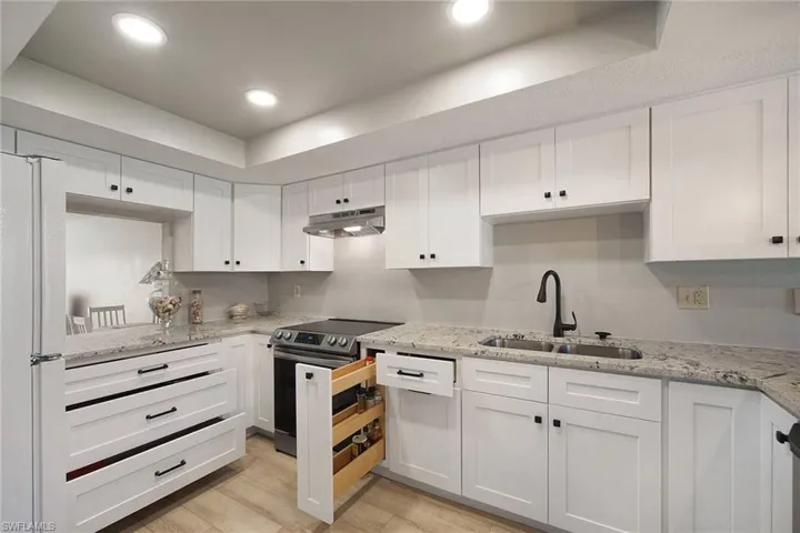 Attractive & Trending White Cabinetry with Bronze hardware, Faucet & Light Fixture over Snack Bar. Dove-tail & Soft-Close Pull Outs