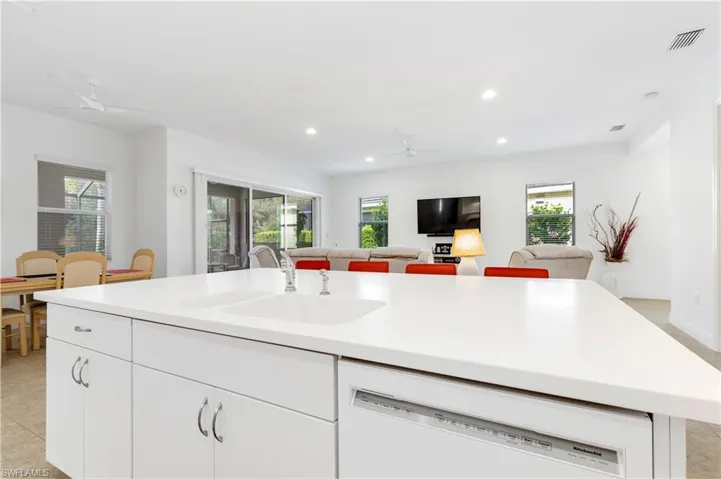 Kitchen featuring a ceiling fan, white dishwasher, white cabinetry, light countertops, and light tile patterned flooring