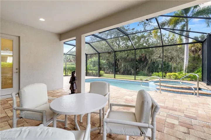 View of patio / terrace with a lanai, an in-ground hot tub, a sunroom, and an outdoor pool