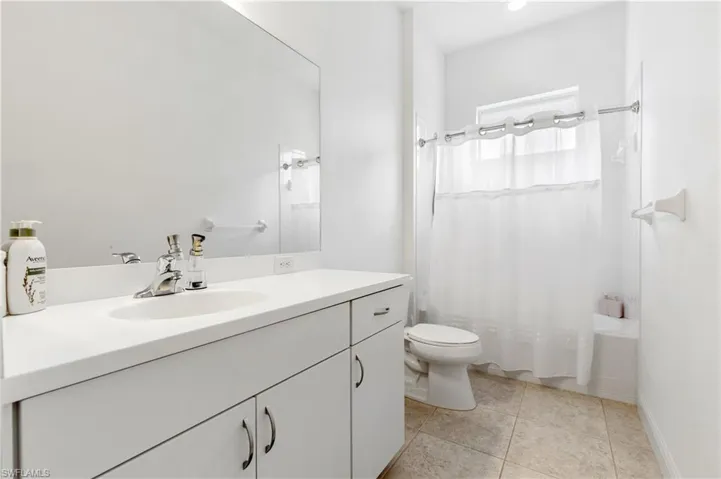 Full bathroom with vanity, shower / bath combination with curtain, and light tile patterned floors