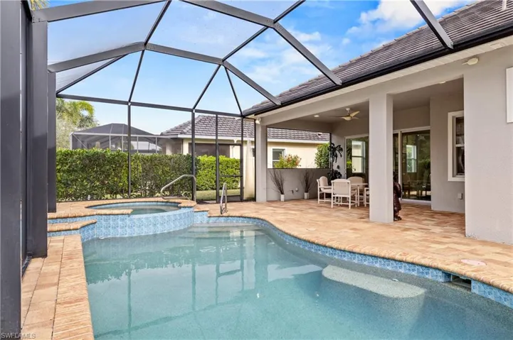 View of swimming pool featuring a patio, a sunroom, glass enclosure, outdoor dining space, and a pool with connected hot tub