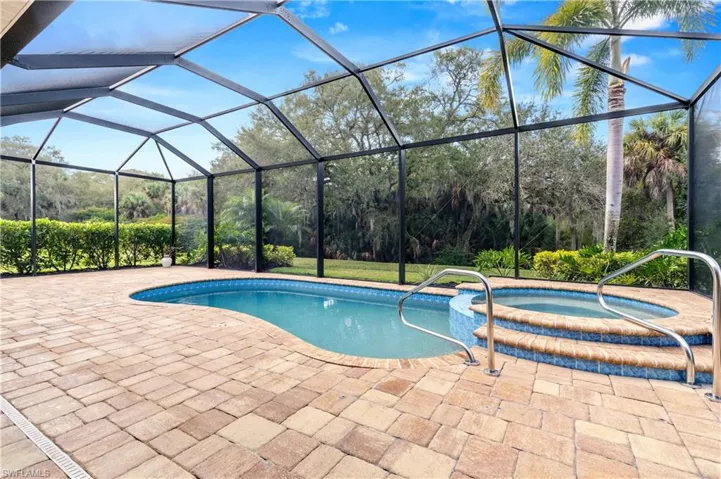 View of swimming pool featuring a lanai, a sunroom, a pool with connected hot tub, and a patio area