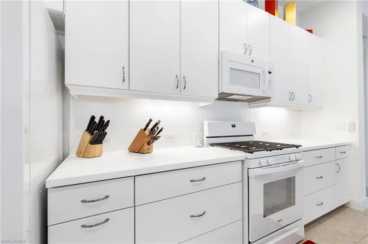 Kitchen with white appliances, white cabinetry, light countertops, and light tile patterned floors