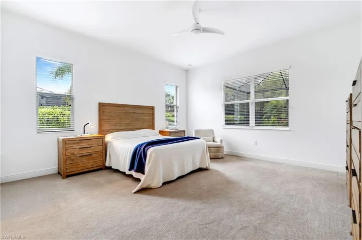 Primary Bedroom featuring multiple windows, light colored carpet, and ceiling fan