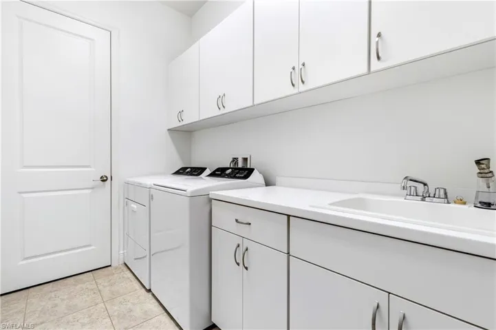 Washroom featuring cabinet space, washer and clothes dryer, and light tile patterned floors