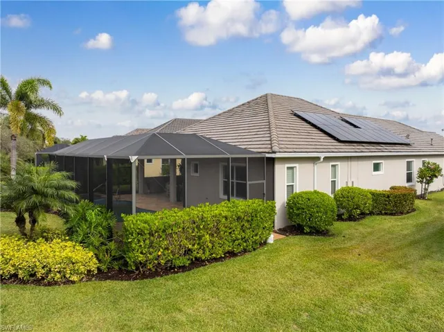 Rear view of house featuring a lanai, a lawn, a sunroom, and stucco siding