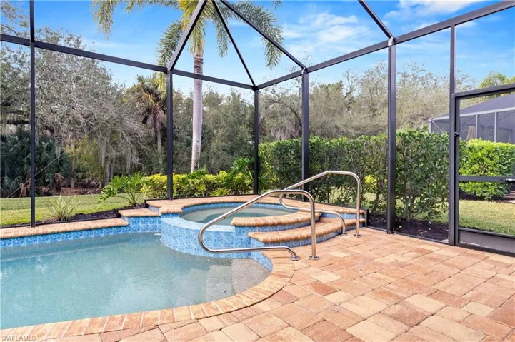 View of swimming pool with glass enclosure, a sunroom, and a pool with connected hot tub
