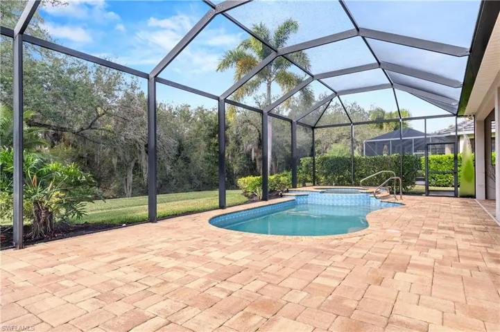 View of pool with a sunroom, glass enclosure, a pool with connected hot tub, and a patio area