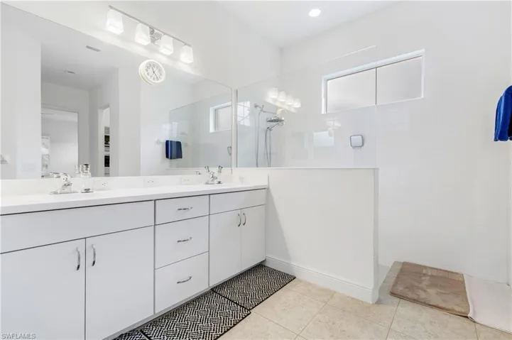 Primary Bathroom with double vanity, a walk in shower, and light tile patterned flooring