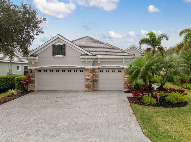 View of front of home featuring stone siding, stucco siding, decorative driveway, and a tile roof