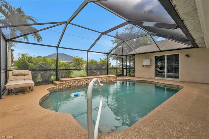 View of pool featuring a patio and glass enclosure