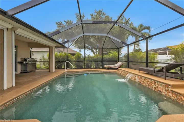 View of swimming pool featuring glass enclosure, a grill, pool water feature, and a patio area