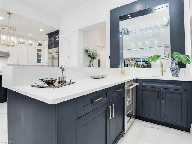 Kitchen with decorative light fixtures, kitchen peninsula, white cabinetry, light tile floors, and built in refrigerator