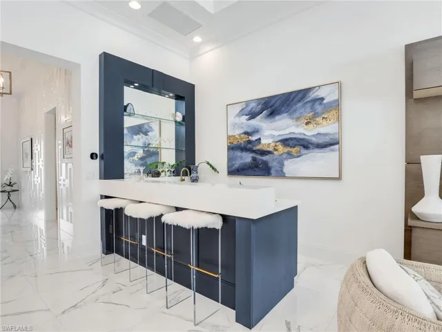 Bar with blue cabinets, light tile flooring, and crown molding