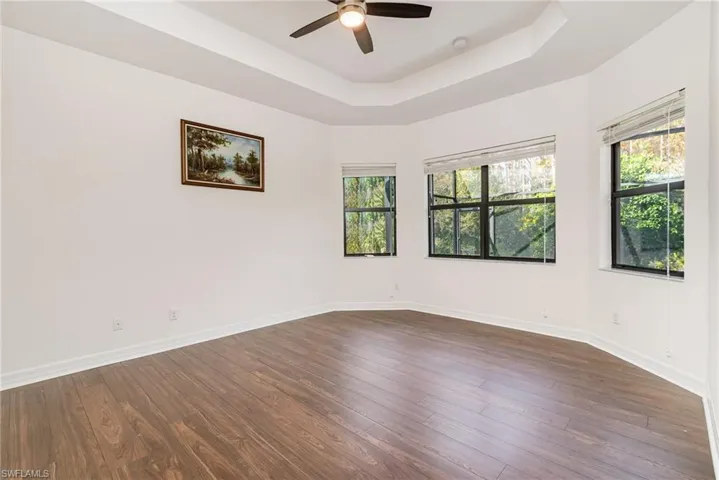 Spare room with dark wood finished floors, a ceiling fan, and a raised ceiling