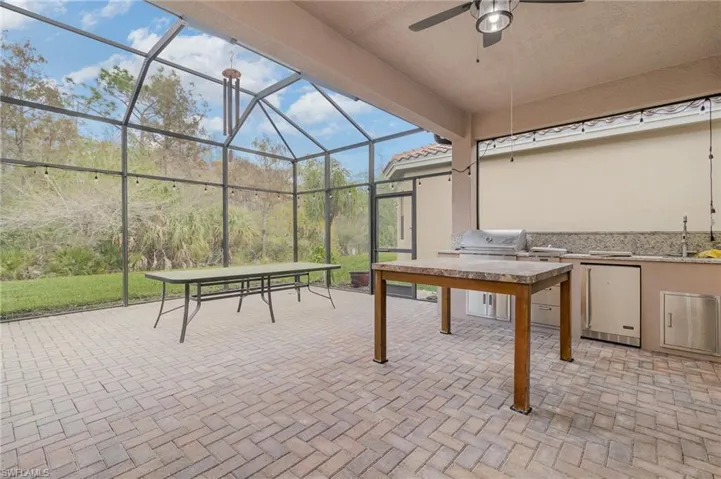 View of patio with exterior kitchen, a sunroom, a lanai, and ceiling fan