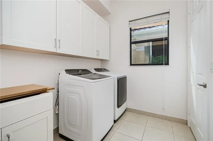 Laundry area with cabinet space, washing machine and clothes dryer, and light tile patterned flooring