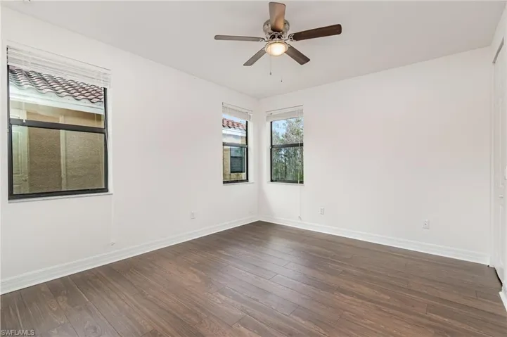 Unfurnished room with dark wood-type flooring and ceiling fan