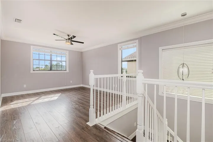 Spare room featuring dark wood finished floors, a ceiling fan, and ornamental molding