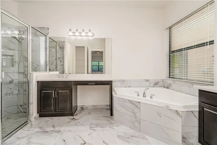 Bathroom with vanity, a marble finish shower, a garden tub, and light marble finish floors